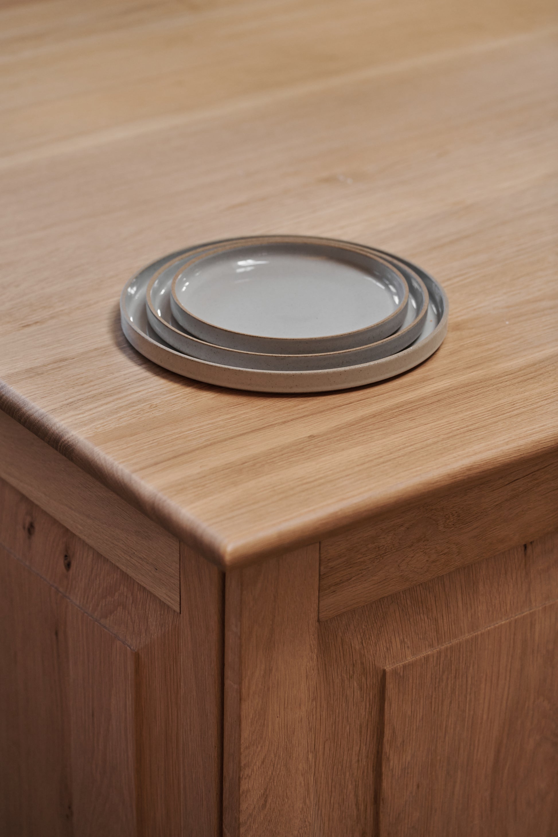 Grey Ceramic Stackable Plates by Hasami Porcelain displayed on wooden tabletop kitchen interior. Japanese-style design clay tableware.