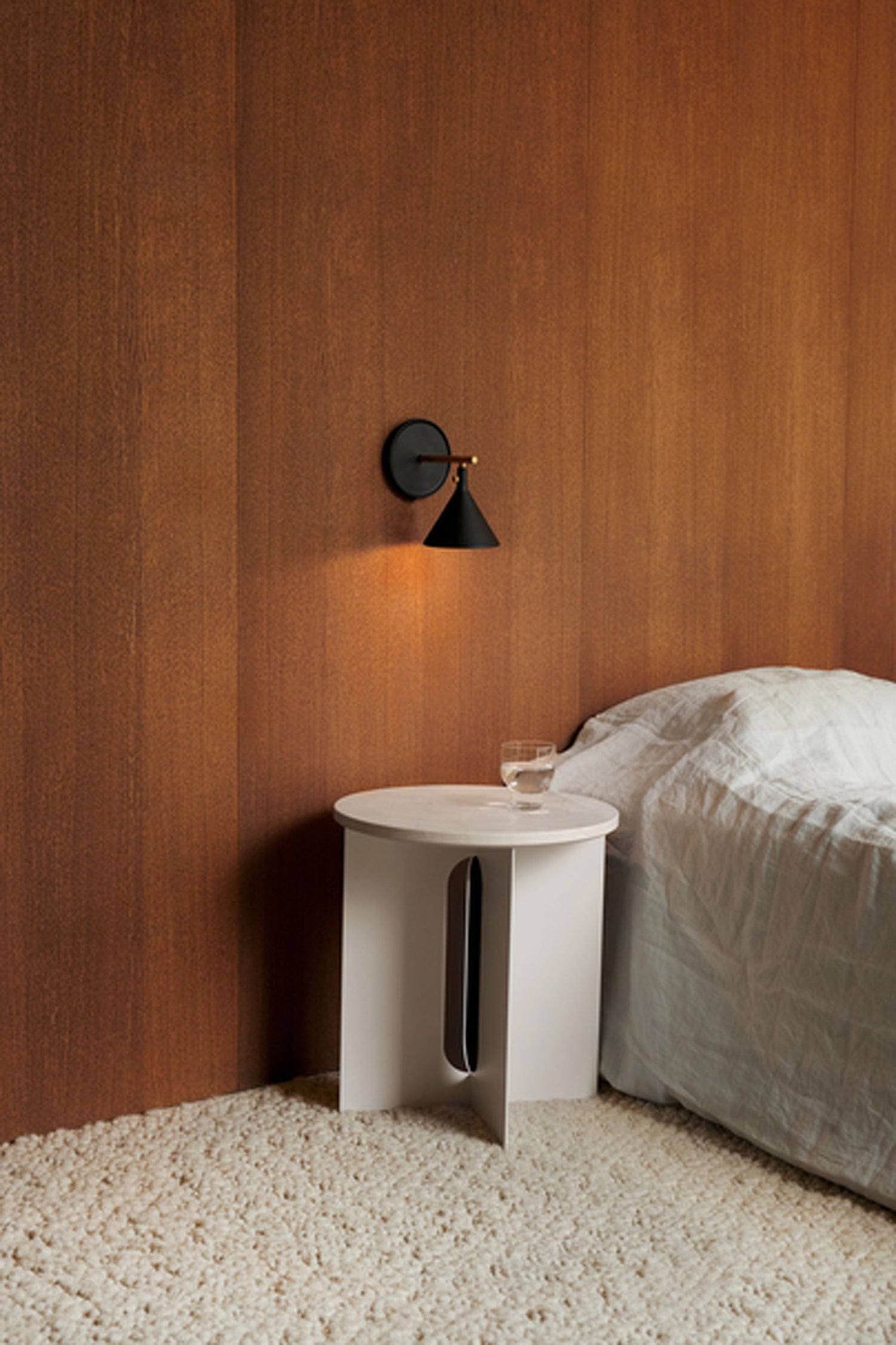 Cast Sconce Wall Lamp Diffuser, dimmer Black by Menu in a bedroom interior setting.