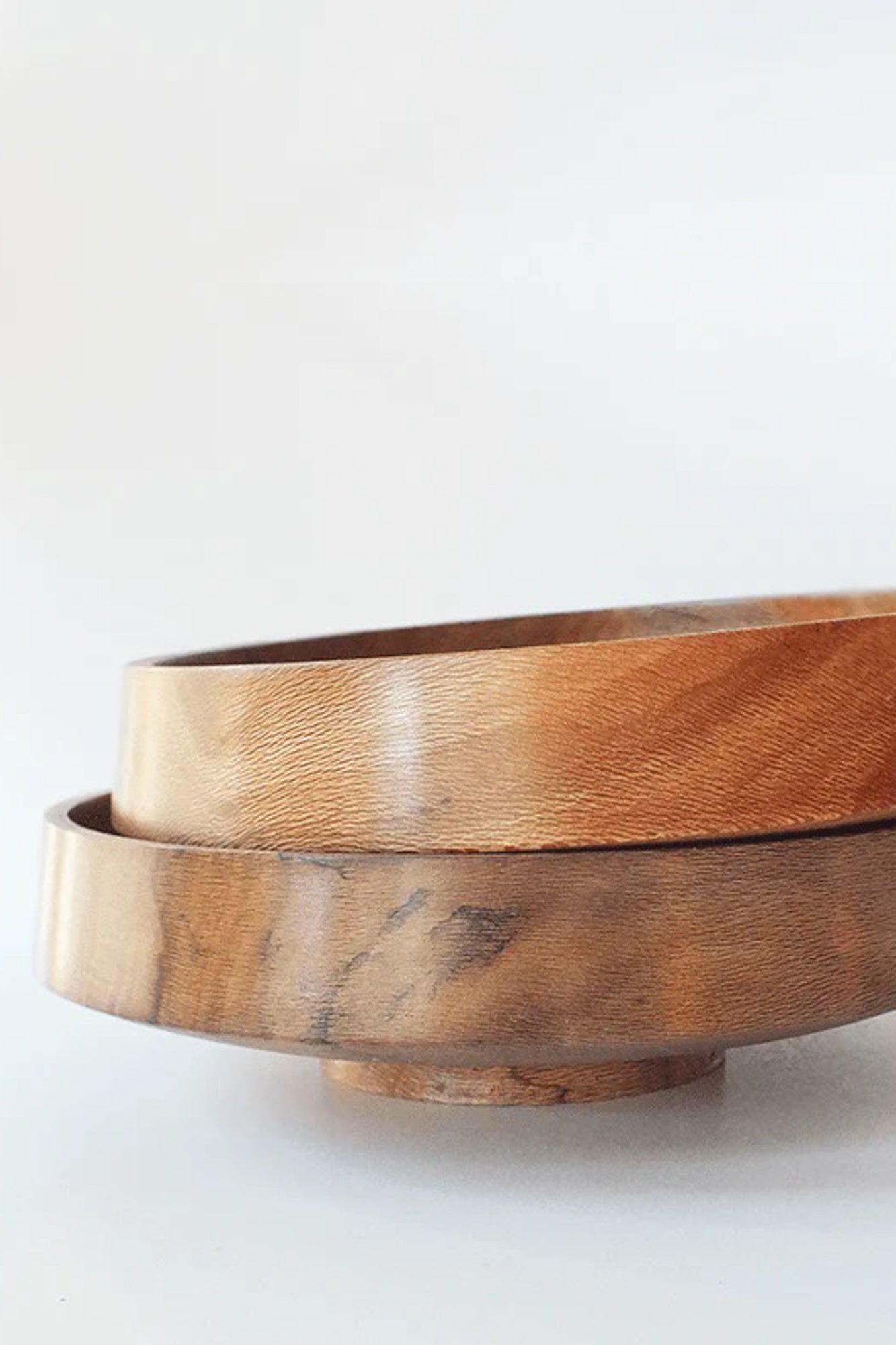 Two bowls of Het Houtlokaal stacked, highlighting its craftsmanship and the natural beauty of sustainably sourced sycamore wood. Handmade in Rotterdam, it embodies the artistry and storytelling of Marisa Klaster, a local woodworker.